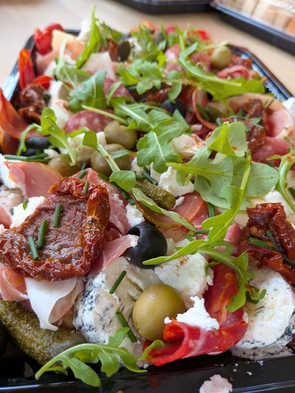 Close-up of an antipasti platter with prosciutto, sun-dried tomatoes, olives and rocket