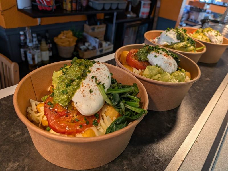 Brunch bowls with a poached egg, pesto, avocado, roasted tomato and spinach