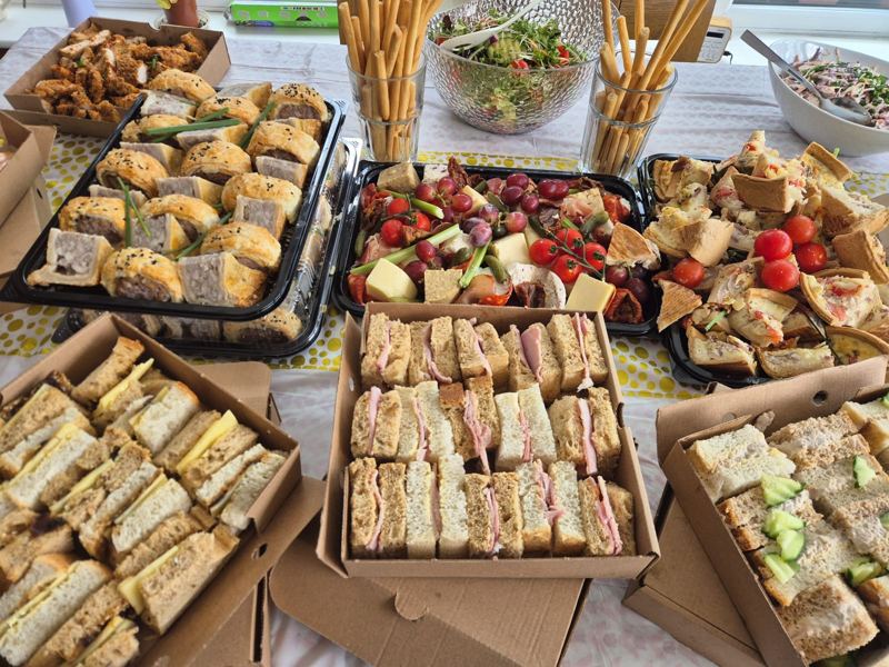 A full buffet spread of sandwiches, sausage rolls, quiche, salad and breadsticks