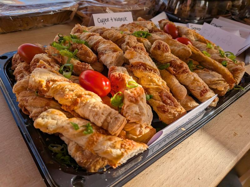 A tray of golden cheese straw twists garnished with spring onion and cherry tomatoes