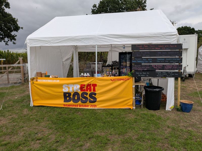 A Streat Boss marquee in a field with a hand-written chalkboard menu