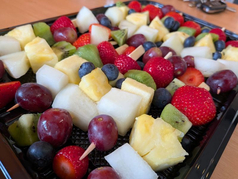 A tray of fruit skewers with strawberries, pineapple, melon, kiwi, grapes and blueberries