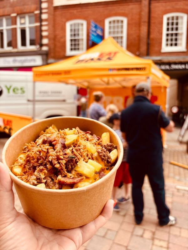 A pot of loaded fries held up in front of the Streat Boss market stall