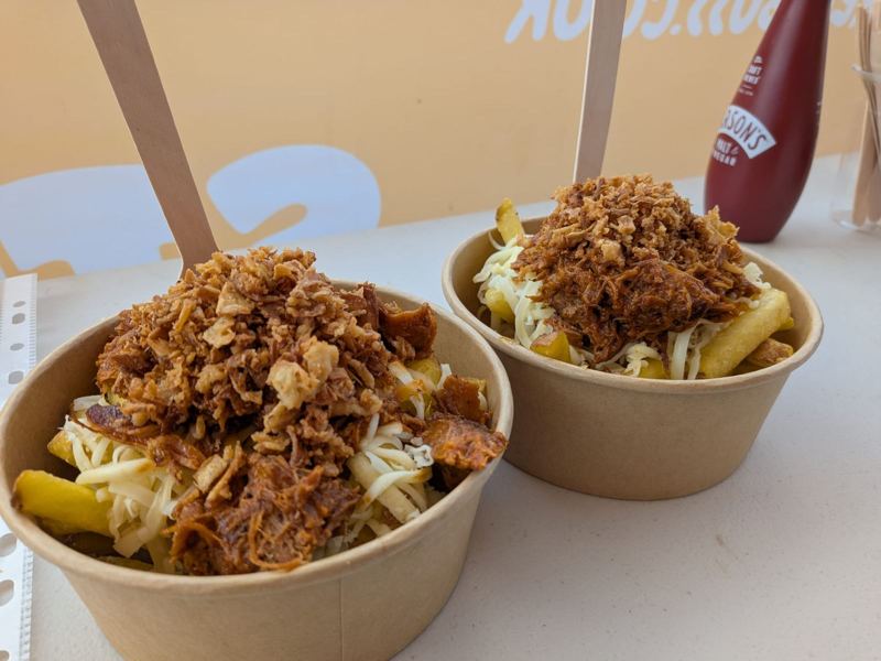 Two bowls of fries loaded with cheese, pulled pork and crispy onions