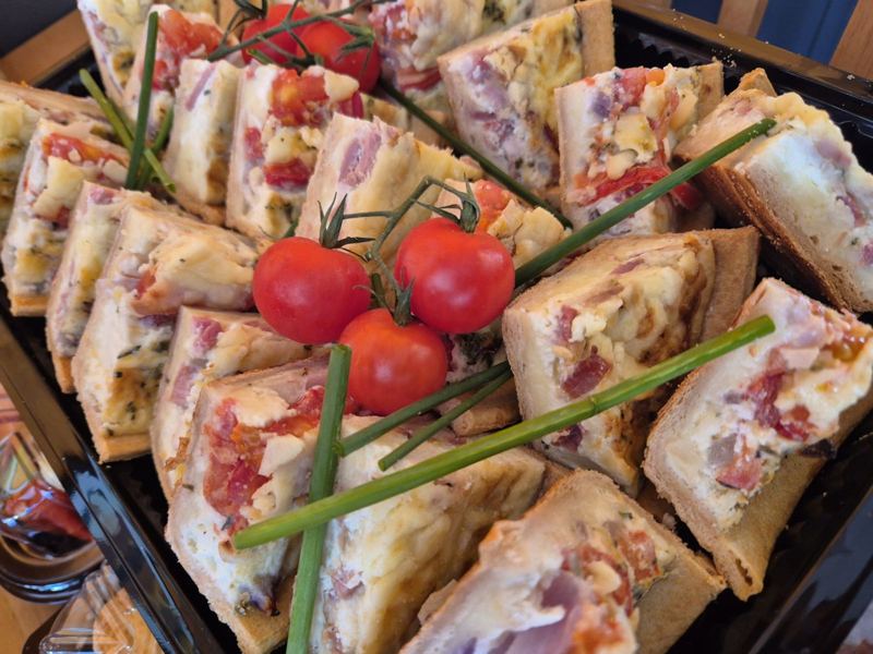 Squares of bacon and tomato quiche garnished with vine tomatoes and chives