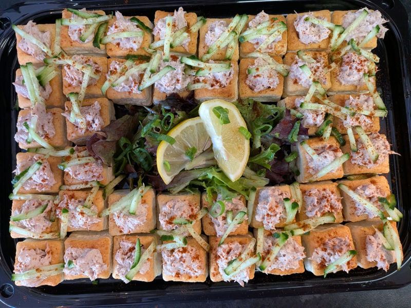 Rows of square vol-au-vents filled with tuna mayo and cucumber around a salad
