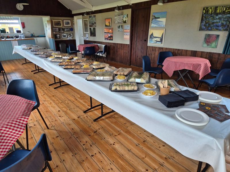 Platters of sandwiches and crisps laid along a buffet table in a village hall