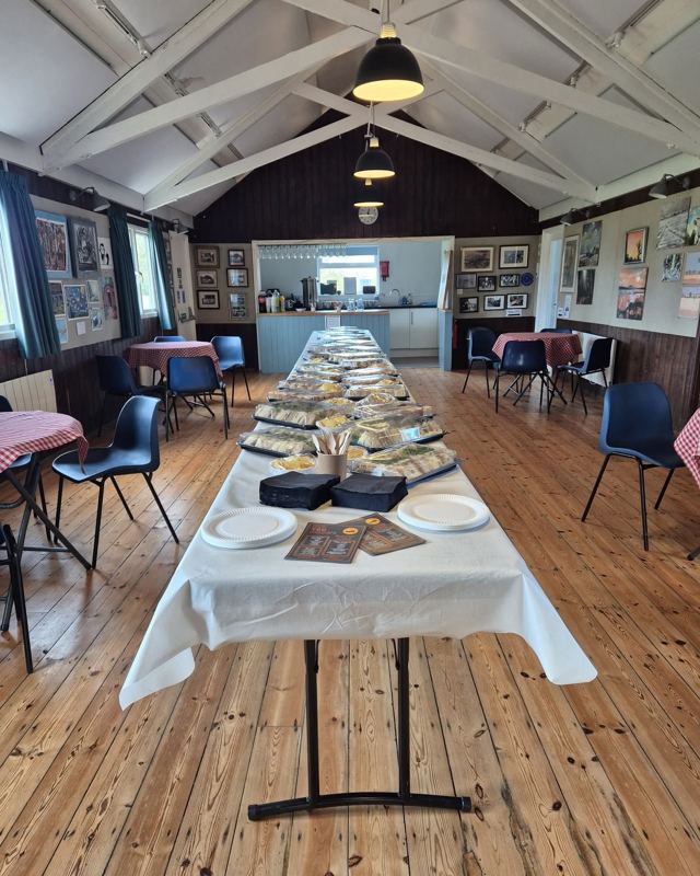 A long buffet table laid out down the middle of a village hall